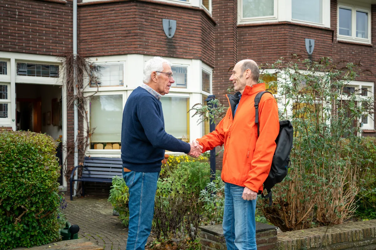 Gesprek tussen twee mensen op straat in een woonwijk, mogelijk over duurzame mobiliteit met de fiets.