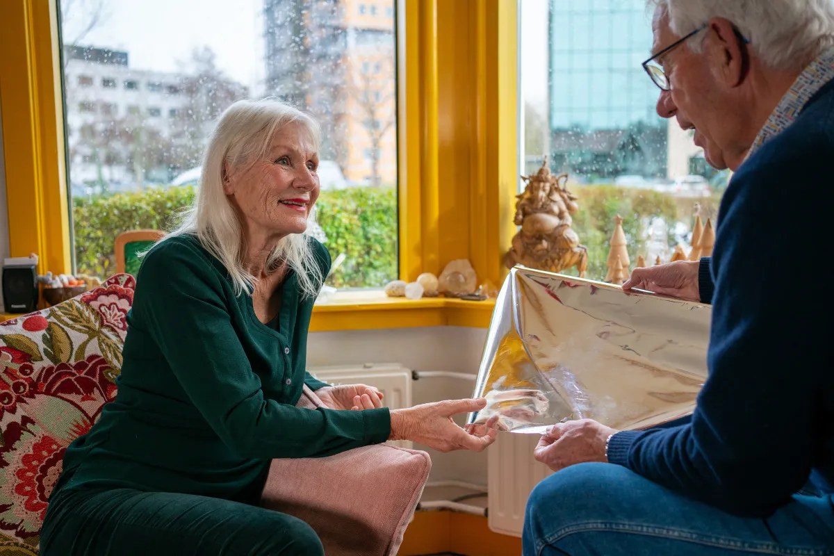 Isolatiefolie die een bewoner helpt warmteverlies via het raam te verminderen wordt getoond tijdens een adviesgesprek.