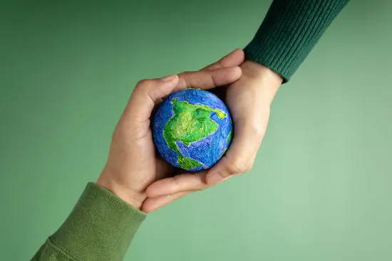 2 handen houden een bal vast. De bal ziet eruit als de wereld.