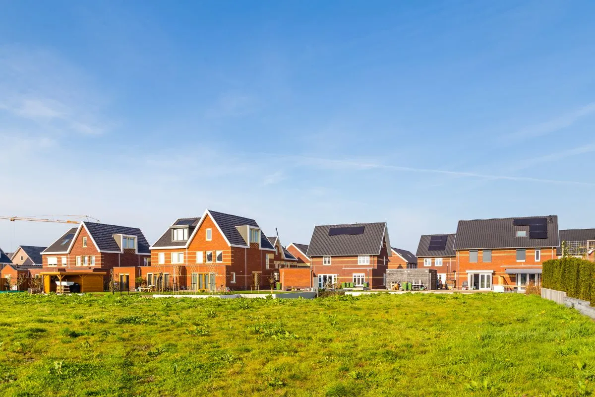 Nieuwbouwwoningen met zonnepanelen op de daken in een groene, open omgeving.