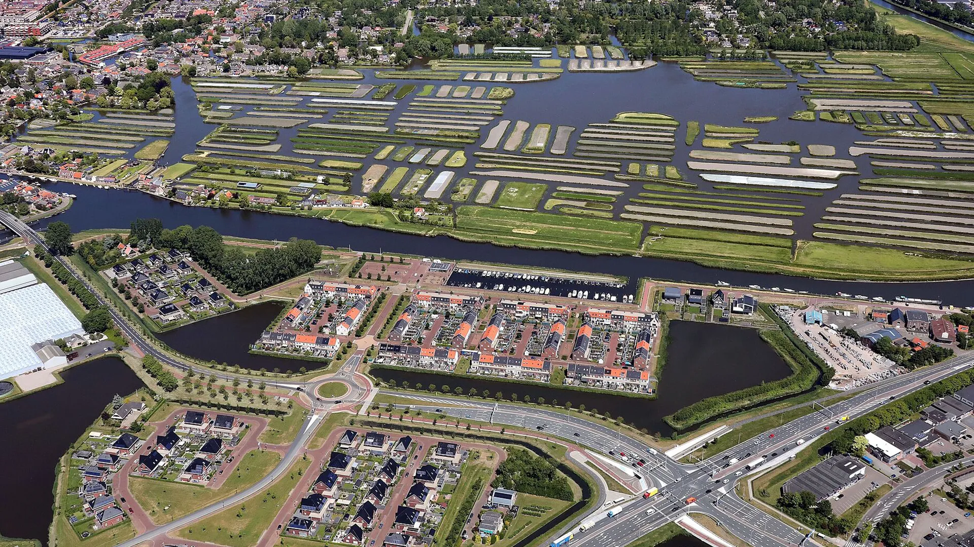 Dijk en Waard met woonwijken, waterpartijen en landbouwpercelen vanuit luchtzicht.