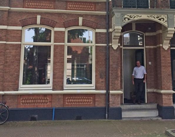 Oud herenhuis met verzakte fundering en man bij de ingang, startpunt van energieneutrale renovatie.