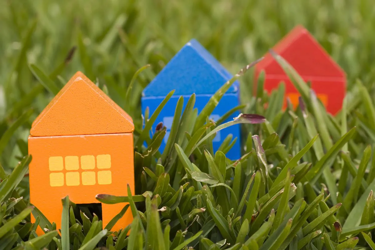 Woningverduurzaming geïllustreerd met kleurrijke houten huisjes in het gras.